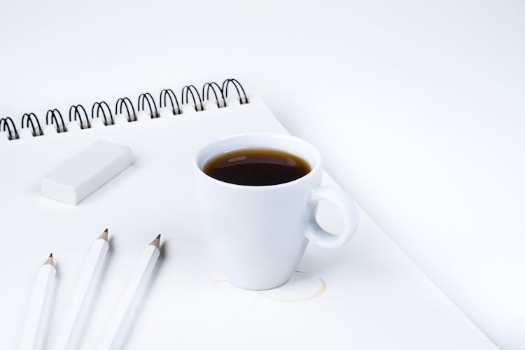 A Cup Of Coffee Near White Pencils