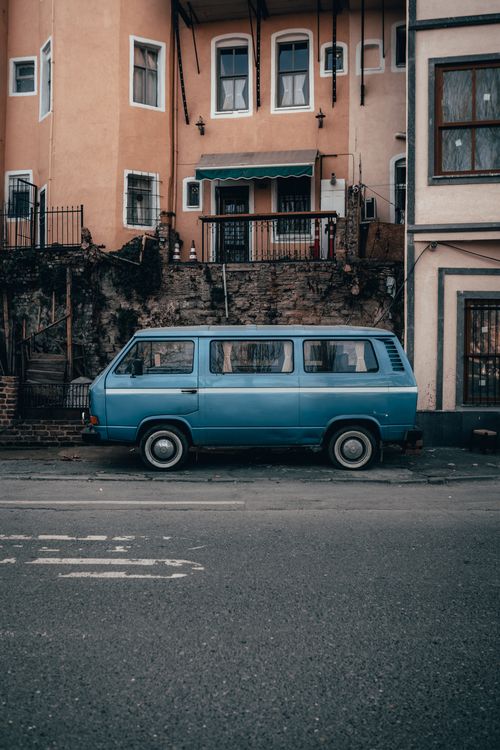Free Retro blue van parked by an old residential building on a quiet urban street. Stock Photo