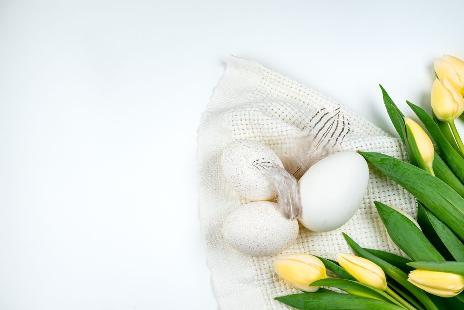 A beautiful spring arrangement with yellow tulips and Easter eggs on a white background.