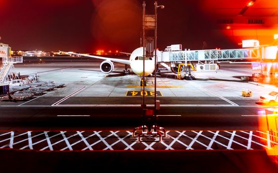 A long exposure of an airplane docked at Abu Dhabi airport at night, highlighting travel and transportation.