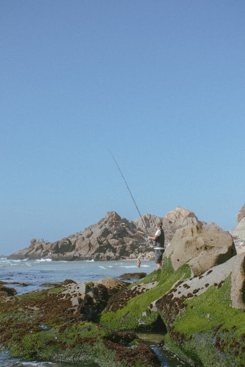 Photo of a Man Fishing on a Rocky Shore