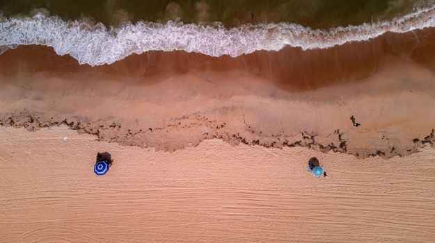 Top-down view of a serene beach in Brazil with waves washing up on the sandy shore.