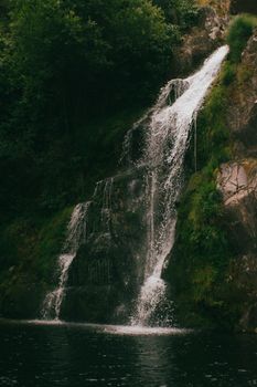 Captivating waterfall flowing through lush green forest, creating a tranquil scene.