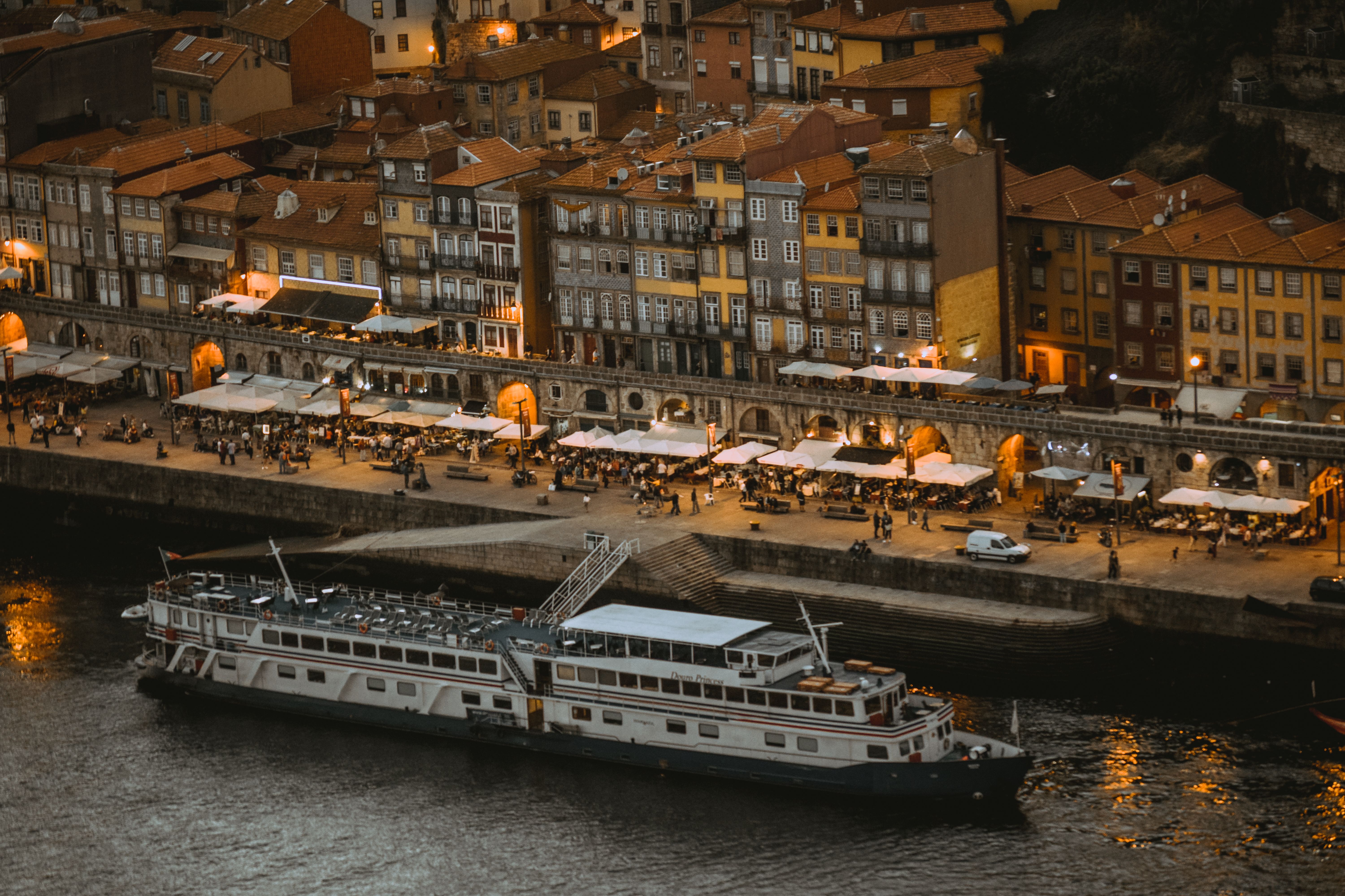 Aerial view of Porto riverside at night with moored cruise ship and vibrant promenade.