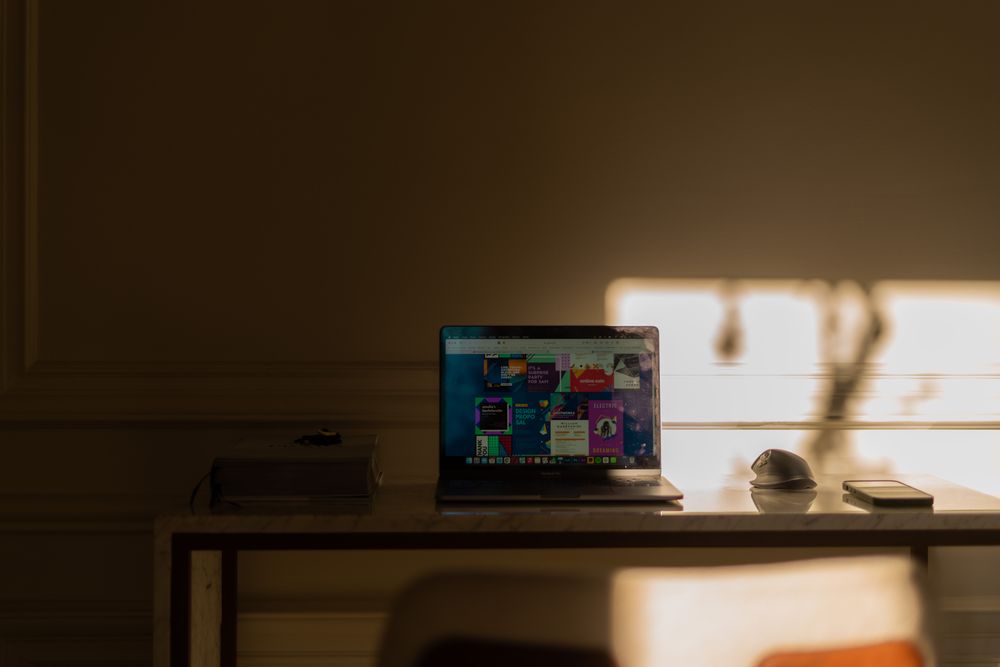 A minimalist workspace with a laptop, mouse, and smartphone in soft daylight