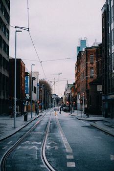 Empty city street with tram lines under overcast skies, capturing urban solitude.
