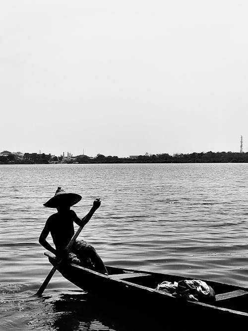 Grayscale Photo of a Person Riding a Boat