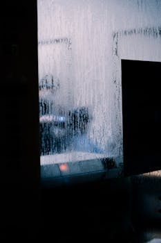 Blurred silhouette through a moist window capturing a mysterious and artistic scene.