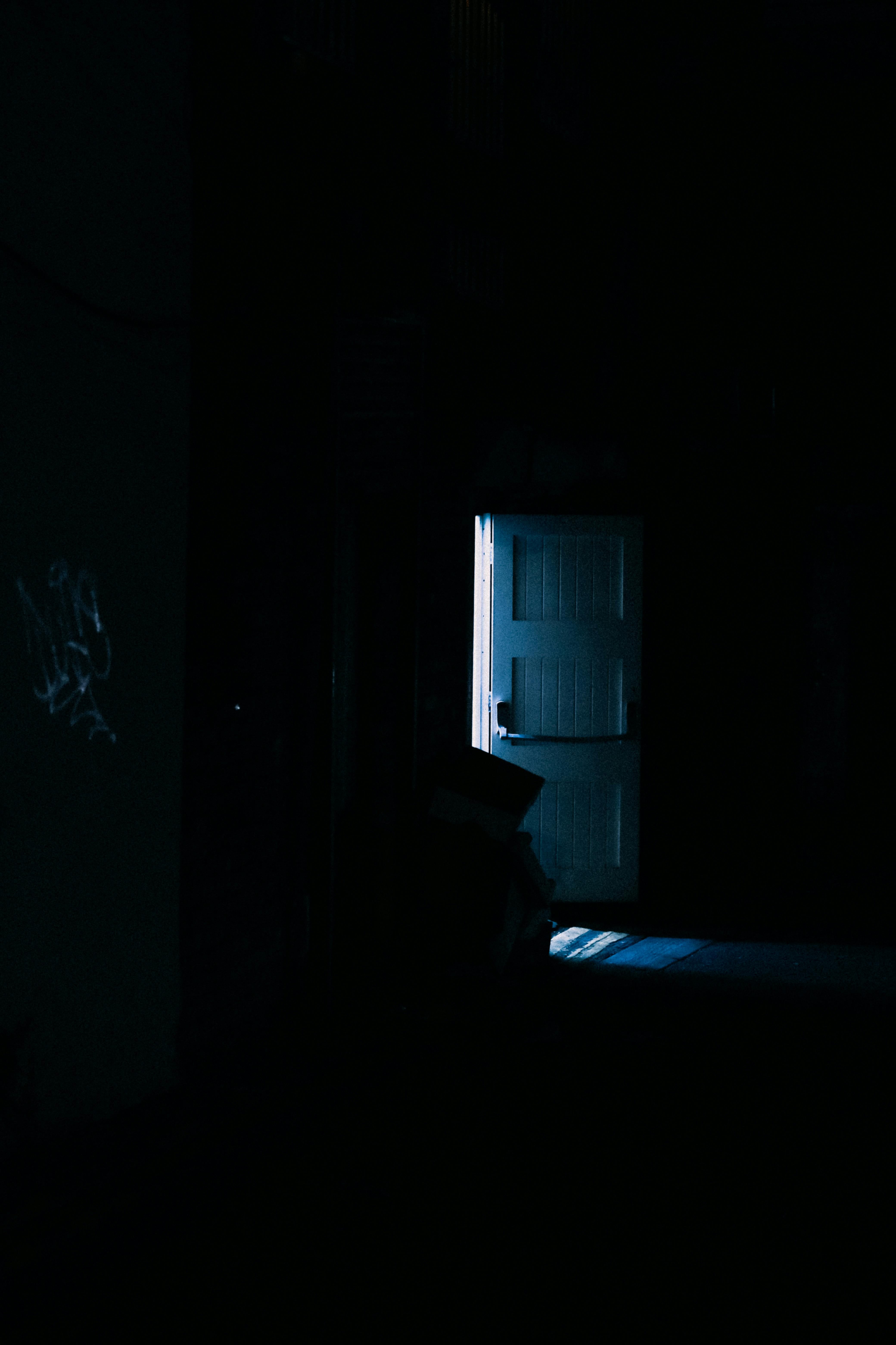 A mysterious doorway in a dimly lit room casts an eerie, spooky atmosphere.