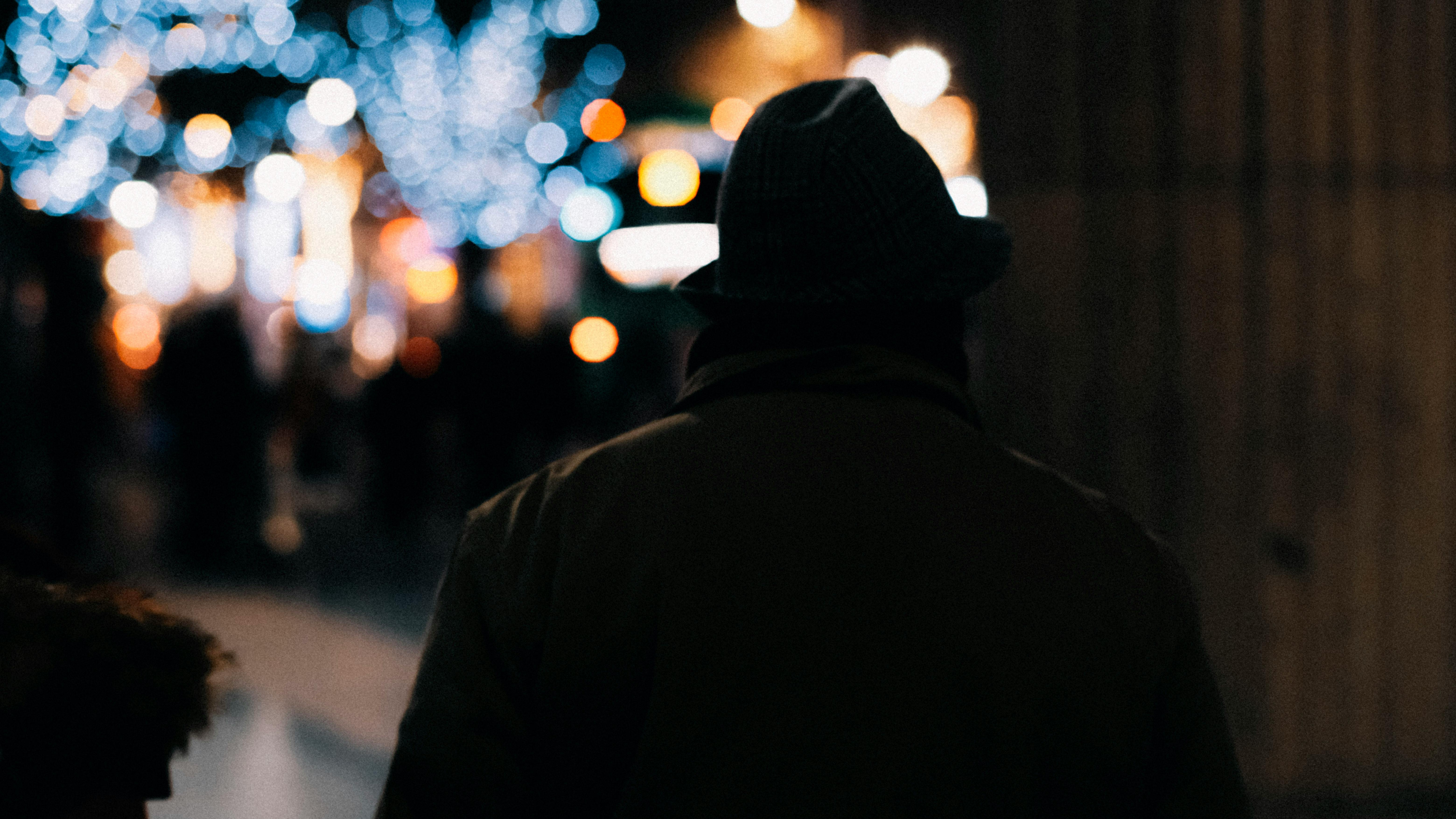 Karanlık ve puslu bir atmosferde, uzaklardaki zayıf bir ışık hüzmesine doğru sessizce ve umutla bakan yalnız bir insan silüeti.