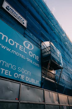 Scaffolding covering building facade with advertisement for Motel One Dublin. Construction underway.