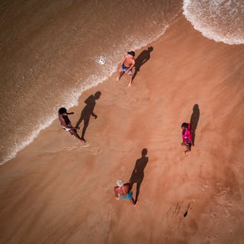 Aerial shot of friends enjoying a game of soccer on the sandy shores of Grussaí, Brazil.