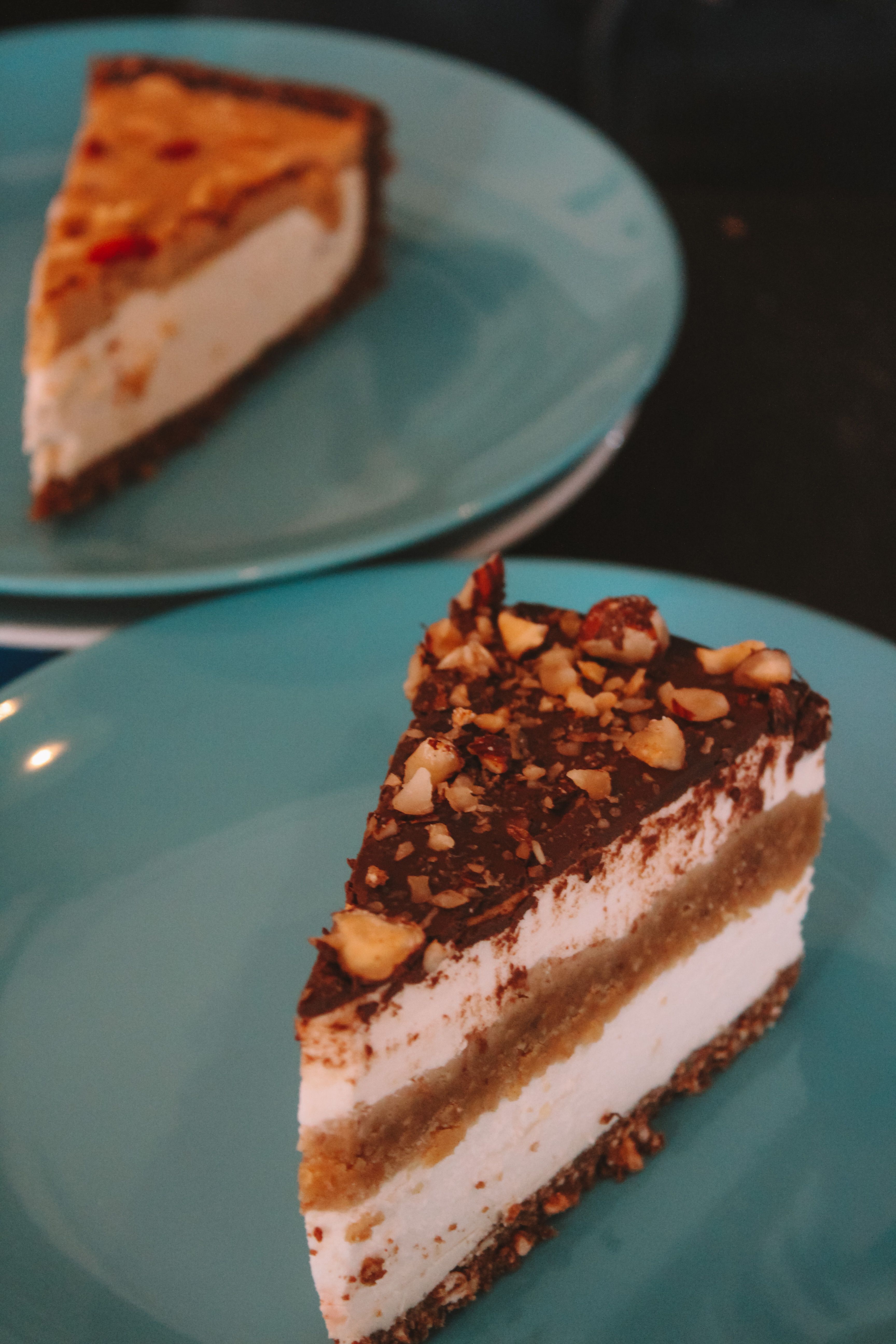Close-up of layered nut cakes with chocolate topping on blue plates.