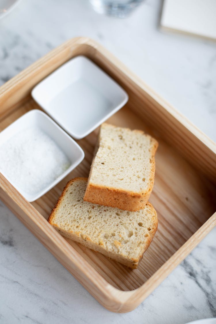 Slices Of Bread Served On Wooden Tray With Salt And Vinegar