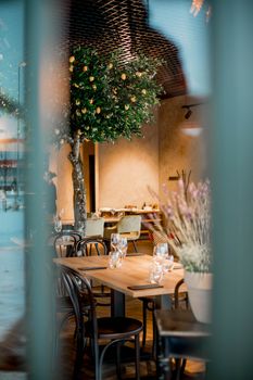 Stylish restaurant interior featuring wooden tables, elegant chairs, and lush indoor plants.