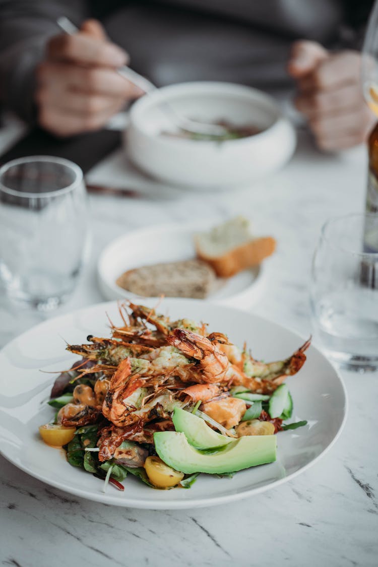 Plate Of Frutti Di Mare Salad With Unrecognizable Person Eating Soup In Background