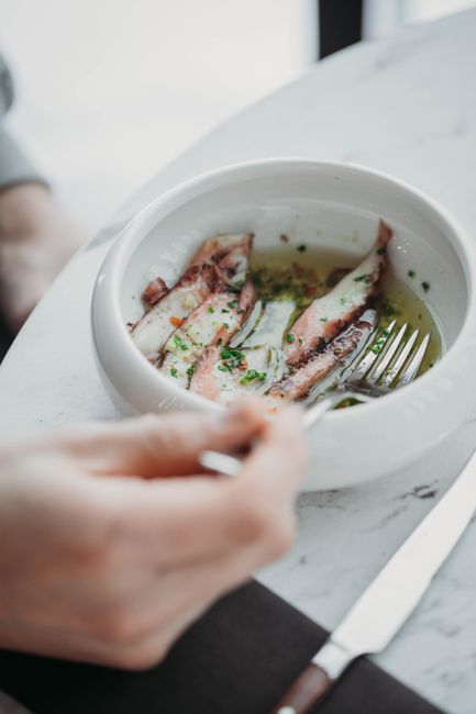 Appetizing close-up view of seafood dish with herbs, served in a bowl with a fork.