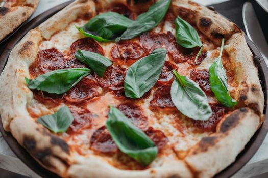 A mouthwatering Italian pepperoni pizza garnished with fresh basil leaves, perfect for a gourmet treat.