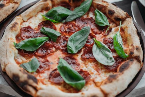 Free A mouthwatering Italian pepperoni pizza garnished with fresh basil leaves, perfect for a gourmet treat. Stock Photo