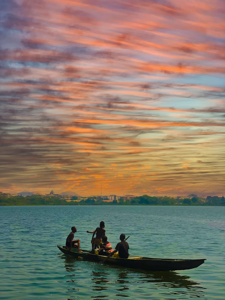 People In A Canoe Boat Sailing In The Ocean During Golden Hour 