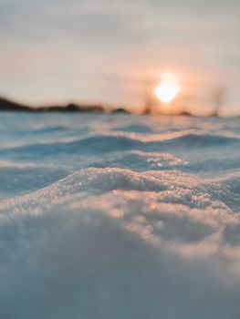 A serene sunset over a snow-covered field during the golden hour, capturing the winter glow.