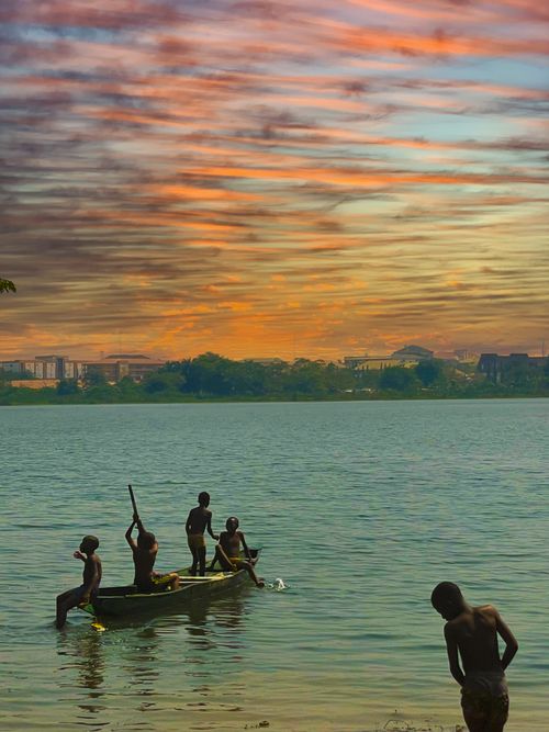 Free Silhouettes of people in a boat on the river under a vibrant sunset sky. Stock Photo