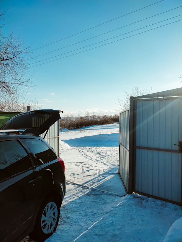 A Black Car Near An Open Gate