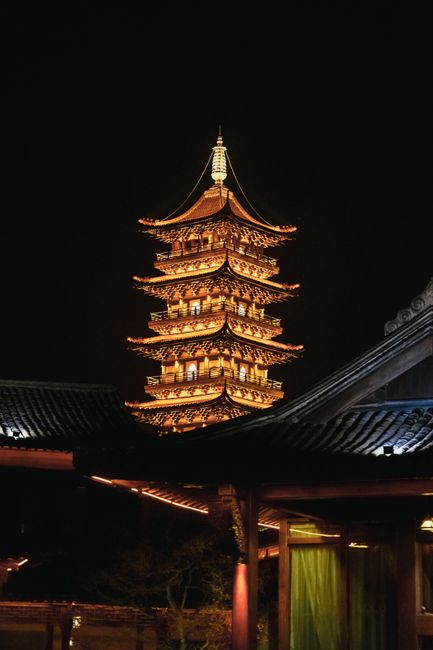 A beautifully lit traditional Chinese pagoda stands tall against the night sky.