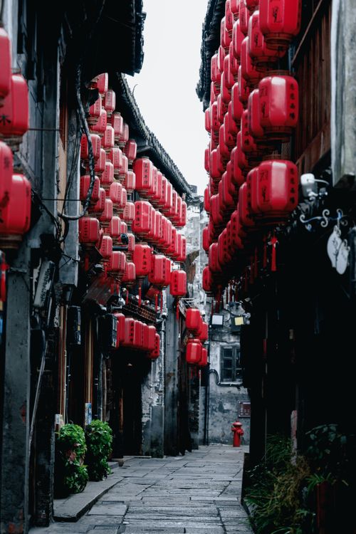 Free A picturesque alley adorned with traditional red lanterns, showcasing the beauty of historic Chinese architecture. Stock Photo