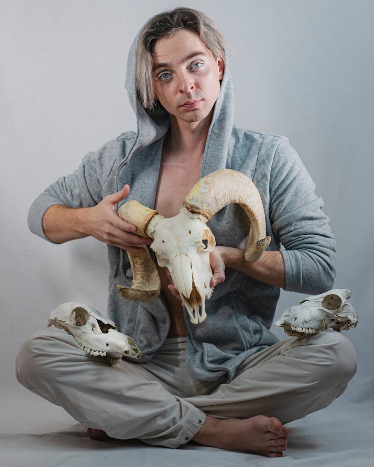 Man In Gray Jacket Holding Animal Skulls