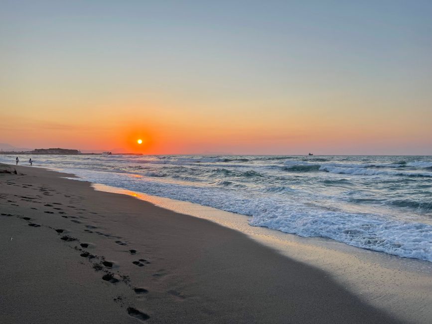 Mediterraans strand bij zonsondergang met golven