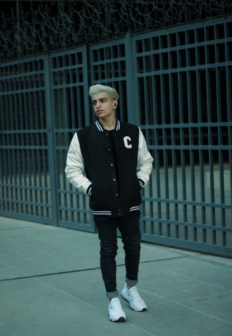 Man In A Varsity Jacket Standing On The Sidewalk