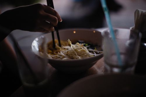 A noodle bowl being eaten with chopsticks — photo by Alexey Demidov on Pexels