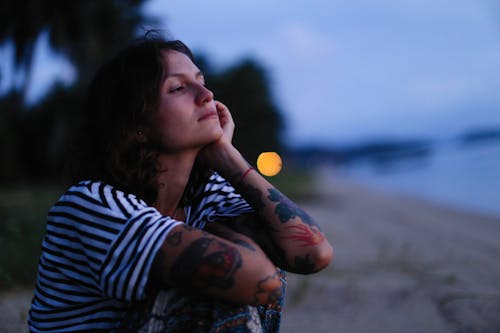 Sad Woman with Tattoos on the Beach