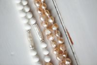 Pearl and bead necklaces on a white surface, photo by Alexey Demidov on Pexels