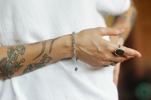 Person with Tattoos Wearing Bracelet and Rings