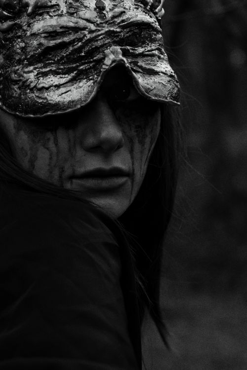 Free A haunting black and white portrait of a masked woman in a dark, eerie forest setting. Stock Photo