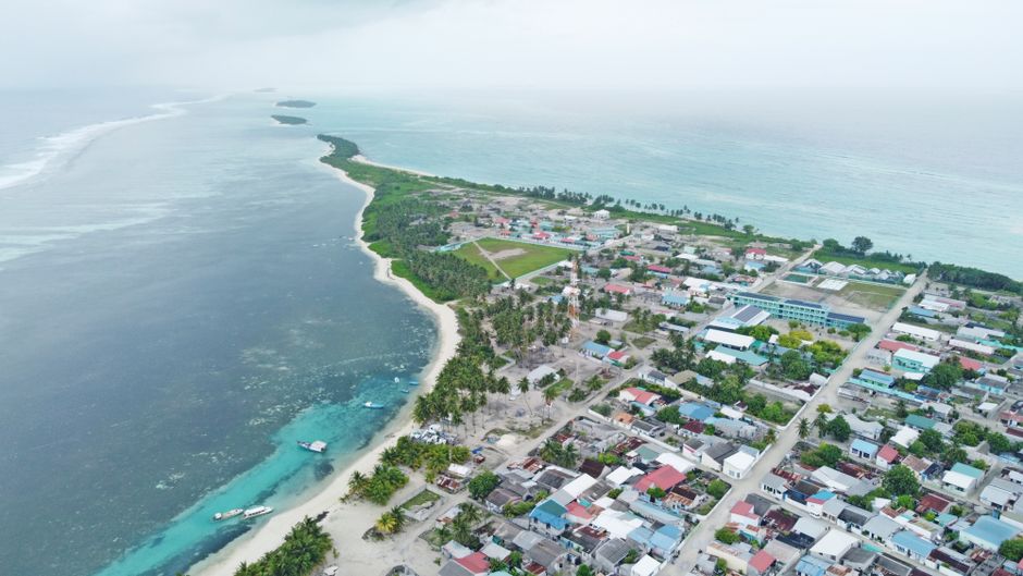 Breathtaking aerial view of a coastal town in Maldives, showcasing the island's lush greenery and clear waters.