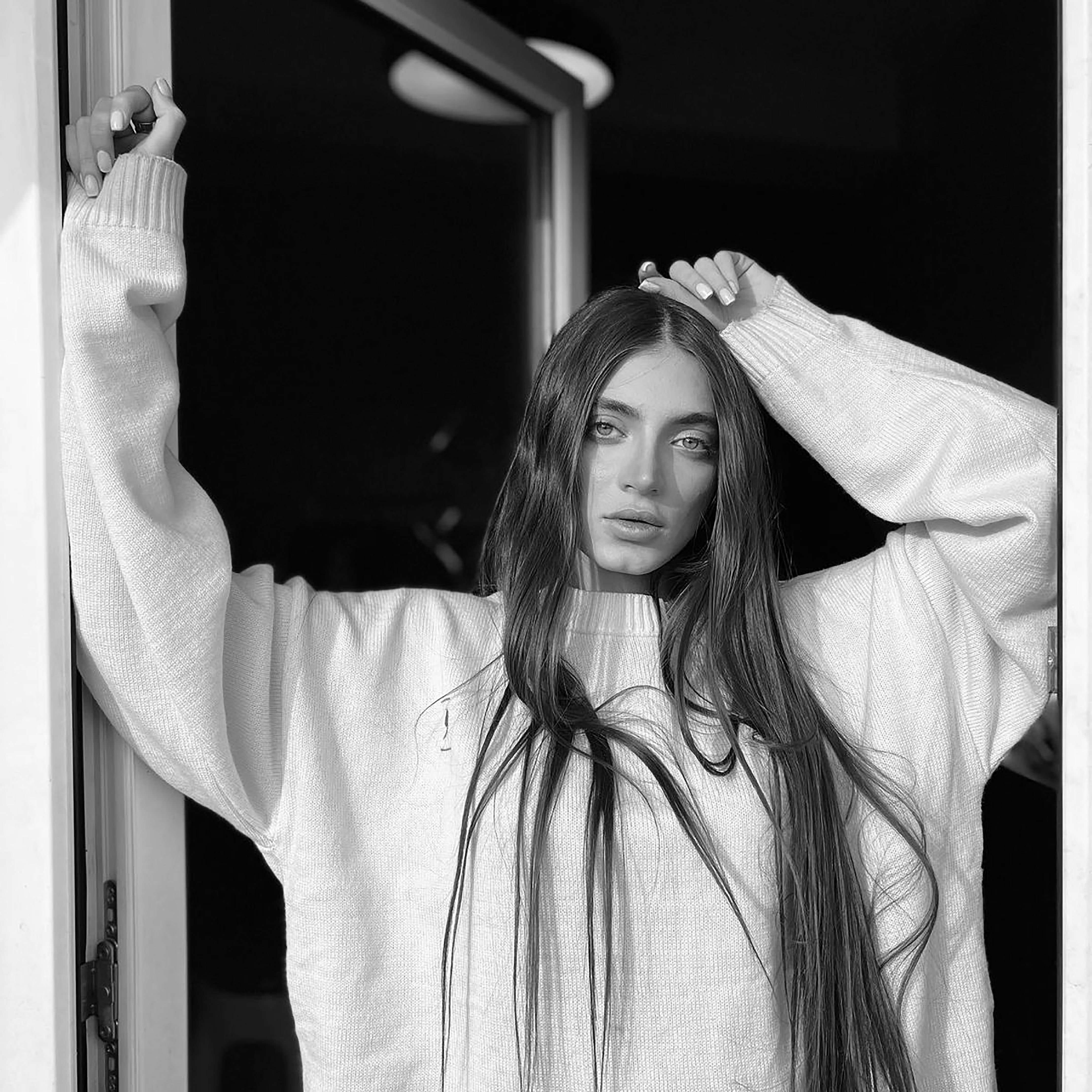 Elegant black and white portrait of a woman in a cozy sweater with long hair.