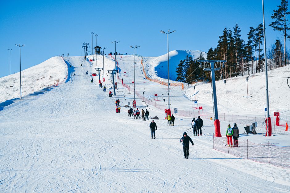 People enjoy a sunny winter day skiing and snowboarding at a bustling ski resort.
