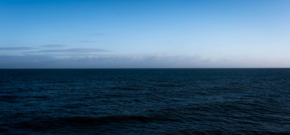 A tranquil ocean view under a twilight sky with calm waters and subtle waves