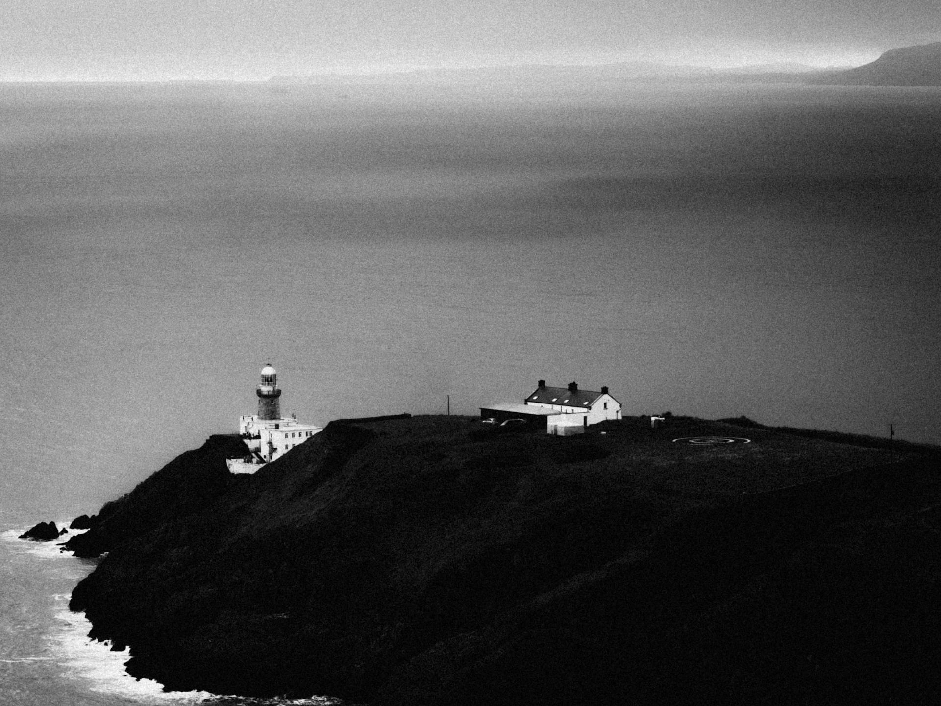 A moody black and white aerial shot of the iconic Baily Lighthouse on Howth Head, Ireland.