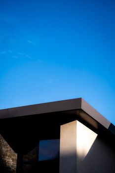 A modern architectural design with a clean and minimalistic facade against a clear blue sky.