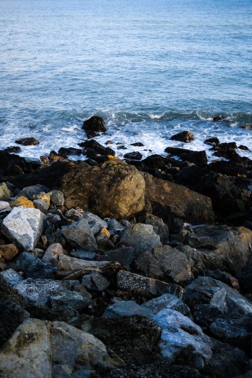 Free A scenic view of a rocky shoreline with waves crashing and ocean backdrop, offering a natural landscape. Stock Photo