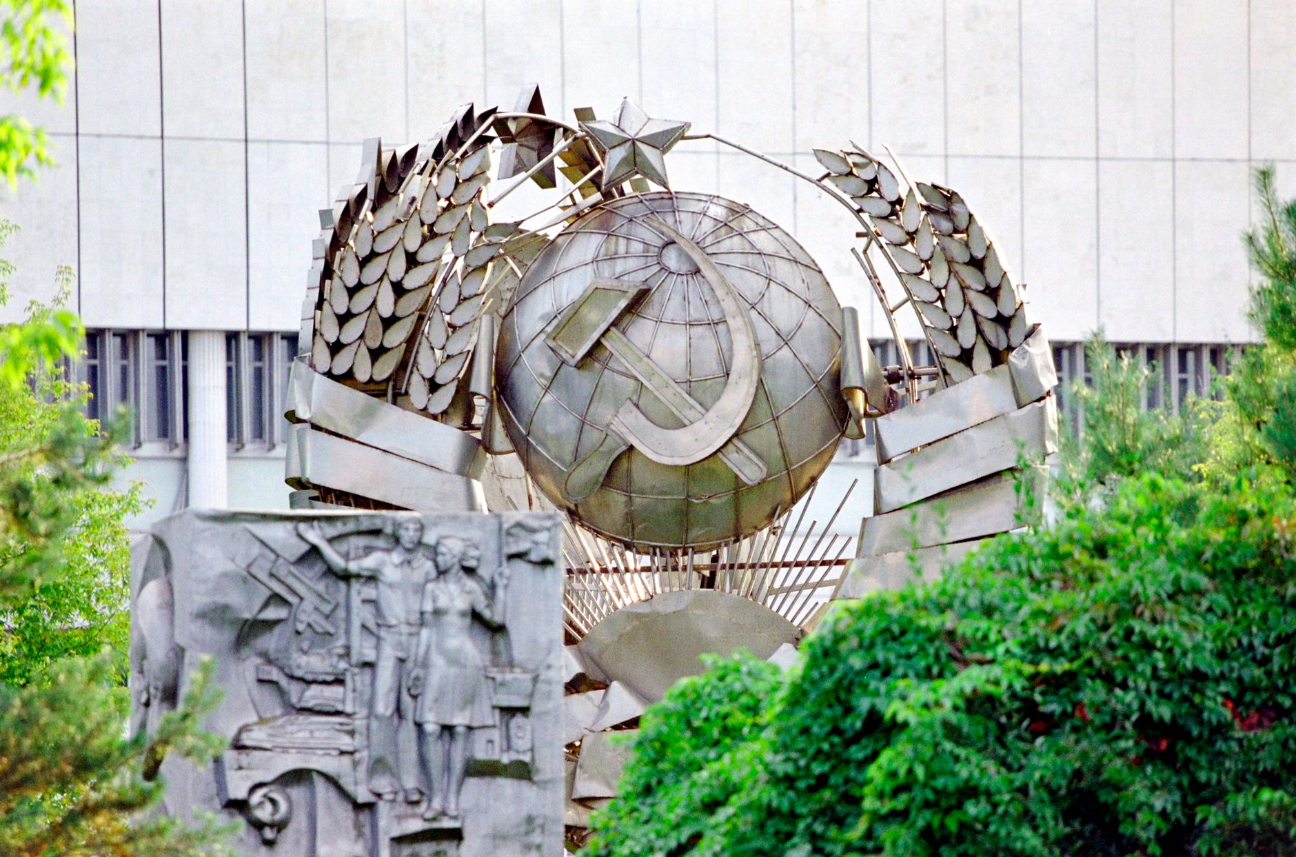 A detailed view of a Soviet sculpture in Moscow, showcasing historical symbolism amidst greenery.
