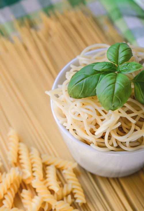 Free Bowl of freshly cooked spaghetti topped with basil leaves, perfect for a tasty Italian meal. Stock Photo