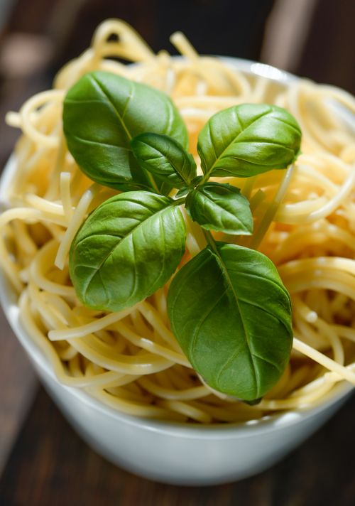 Free Close-up of fresh basil leaves on a bowl of spaghetti, highlighting traditional Italian cuisine. Stock Photo