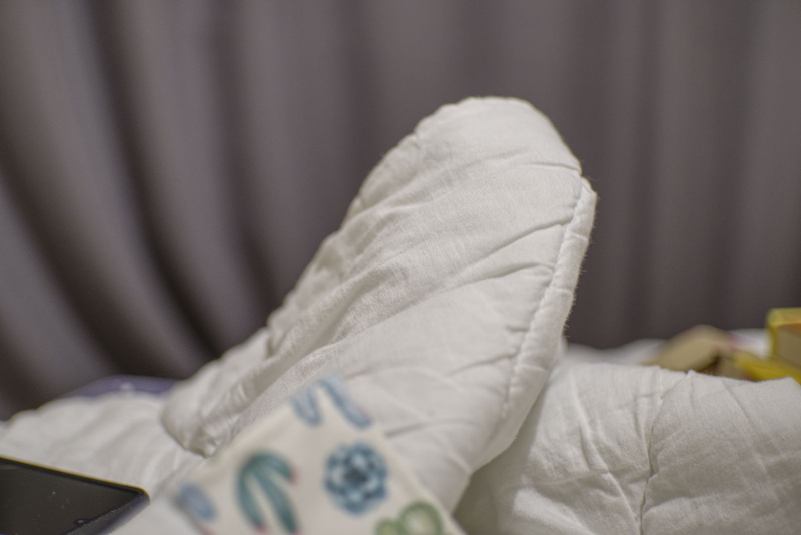 Couette blanche sur un lit devant des rideaux gris