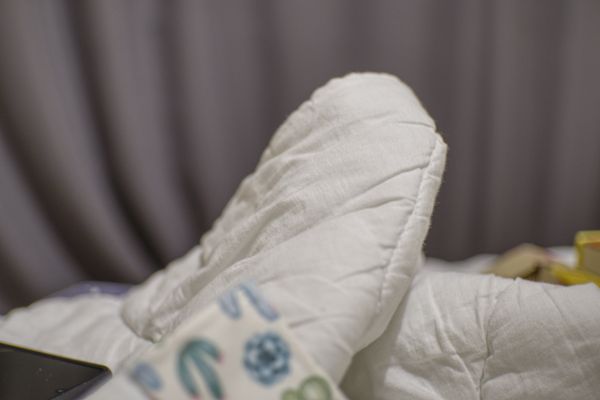 Couette blanche sur un lit devant des rideaux gris