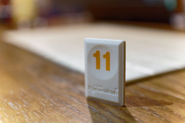 Rummy tile number 11 standing on a wooden table
